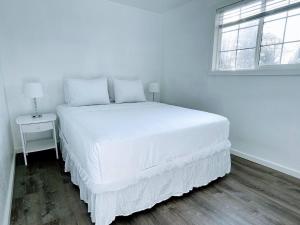 a white bed in a white bedroom with a window at The Sitka Spruce House in Forks