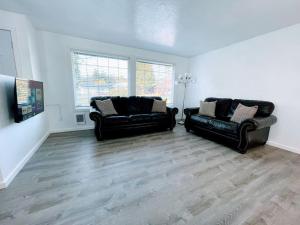 a living room with two black leather couches at The Sitka Spruce House in Forks