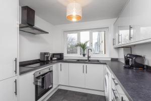 a kitchen with white cabinets and a sink and a window at Well Presented 3 Bedroom, Grangemouth. in Falkirk +14 photos