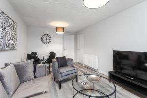 a living room with a couch and a tv and a table at Well Presented 3 Bedroom, Grangemouth. in Falkirk