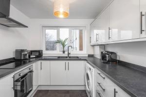 a kitchen with white cabinets and a sink at Well Presented 3 Bedroom, Grangemouth. in Falkirk