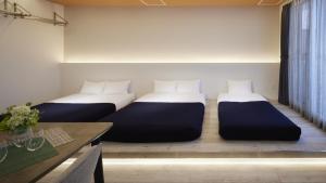 two beds in a room with a table at Minn Chitose in Chitose +3 photos