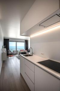 a kitchen with white cabinets and a view of the ocean at Studio Zeezicht in Ostend