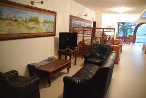 ein Wohnzimmer mit schwarzen Ledermöbeln und einem TV in der Unterkunft Hotel Portal del Sol in Asunción