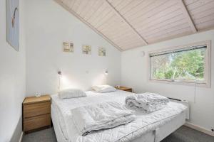 ein weißes Schlafzimmer mit einem Bett und einem Fenster in der Unterkunft FA037 Faxe Ladeplads - Strandlodden 54 in Fakse Ladeplads