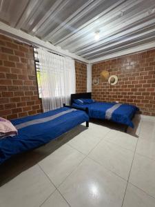 een slaapkamer met twee bedden en een bakstenen muur bij Finca Cimarrones Robles 