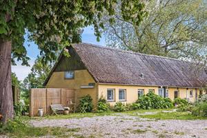 een geel huis met een bruin dak en een hek bij 4320-Stege-Oddermose-Strandvej-5-B in Stege