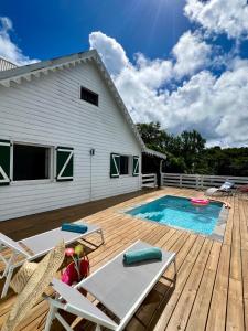 eine Terrasse mit einem Pool und Stühlen sowie ein Haus in der Unterkunft Villa with pool and panoramic view in Rivière-Pilote