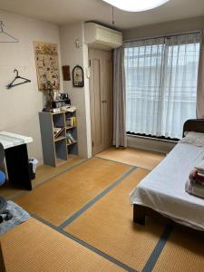 ein Schlafzimmer mit einem Bett und einem großen Fenster in der Unterkunft Okegawa Quiet Homestay in Okegawa