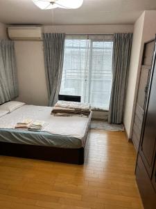 ein Schlafzimmer mit einem Bett und einem großen Fenster in der Unterkunft Okegawa Quiet Homestay in Okegawa