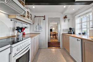 een keuken met witte apparatuur en een eetkamer bij FA004-Faxe-Ladeplads-Brandskov-4 in Fakse Ladeplads +15 foto's