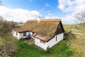 een oud huis met een roestig dak op een groen veld bij FA004-Faxe-Ladeplads-Brandskov-4 in Fakse Ladeplads