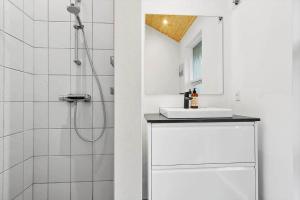 een witte badkamer met douche en wastafel bij 2305-Stege-Thujavej-2 in Stege +18 foto's