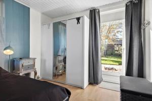 een slaapkamer met een grote glazen deur met een spiegel bij S718-Stroby-Svalemosevej-18 in Strøby