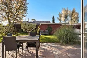 een patio met een houten tafel en stoelen bij S718-Stroby-Svalemosevej-18 in Strøby