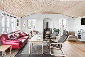 een woonkamer met een rode leren bank en een open haard bij 8207-Vordingborg-Strandparken-22 in Vordingborg