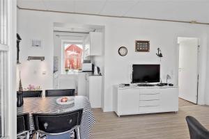 ein weißes Wohnzimmer mit einem Tisch und einem TV in der Unterkunft 4106 Borre - Klintholm Havneby 6 in Borre
