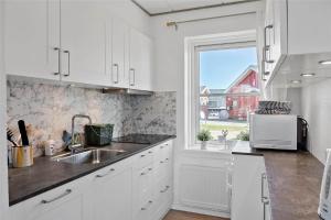 eine weiße Küche mit Spüle und Fenster in der Unterkunft 4106 Borre - Klintholm Havneby 6 in Borre