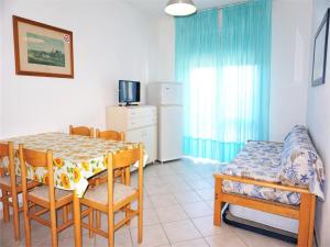 a dining room with a table and chairs and a television at Caorle Holiday Home with Terrace in Porto Santa Margherita di Caorle