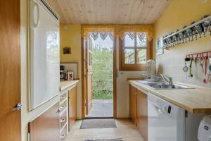 een keuken met een wastafel en een deur naar een tuin bij 3053-Stege-Tjaeregryden-25 in Stege