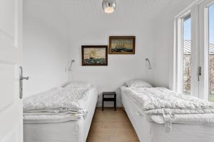twee bedden in een witte kamer met een raam bij S701-Stroby-Kystvejen-164 in Strøby