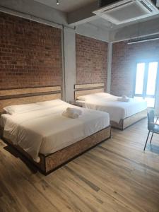 deux lits dans une chambre avec un mur de briques dans l'établissement Brick Box Hotel - Riverside, à Ipoh