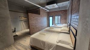 une chambre avec deux lits et un mur de briques dans l'établissement Brick Box Hotel - Riverside, à Ipoh
