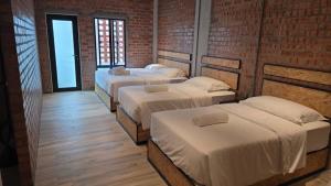 une rangée de 4 lits dans une chambre dans l'établissement Brick Box Hotel - Riverside, à Ipoh