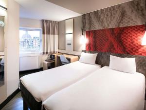 een hotelkamer met twee bedden en een raam bij ibis Amsterdam Centre in Amsterdam