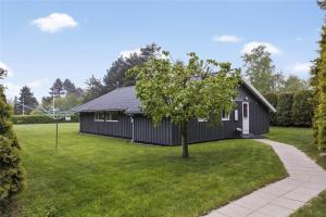 een zwart huis met een boom in de tuin bij 3313-Stege-Overlid-11 in Stege