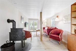 een woonkamer met een houtkachel en rode stoelen bij FA009-Faxe-Ladeplads-Brandskov-6 in Fakse Ladeplads