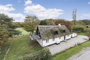een oud huis met een rieten dak in een veld bij FA009-Faxe-Ladeplads-Brandskov-6 in Fakse Ladeplads