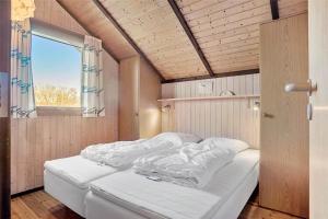 a bed with white sheets in a room with a window at 3078-Stege-Maegleren-18 in Stege