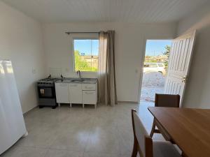 een keuken met een wastafel, een fornuis en een tafel bij Loft novo e bem localizado in Biguaçu