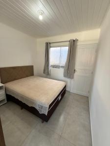een slaapkamer met een bed en een raam bij Loft novo e bem localizado in Biguaçu