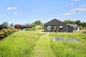 una casa nera in mezzo a un campo di 8218-Lundby-Soloje-Strandvej-20 a Lundby