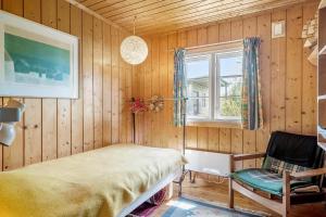 a bedroom with a bed and a chair and a window at 7057-Bogo-By-Mollebakken-67 in Bogø By
