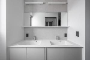 a white bathroom with two sinks and a mirror at Hoshiyado Higashikawa in Higashikawa