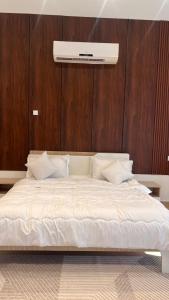 een groot wit bed met een houten muur bij Riva chalet in Badīyah