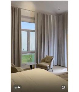 een slaapkamer met een bed, een stoel en een raam bij Riva chalet in Badīyah