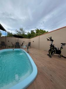a hot tub on a patio with a scooter on a deck at Habitación Maninha in Pântano Grande