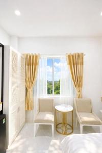 a bedroom with a bed and two chairs and a window at Đại Phú Hotel Hồ Chí Minh in Ho Chi Minh City