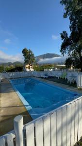 een zwembad naast een wit hek bij Cabañas Granja Paraíso in Molina