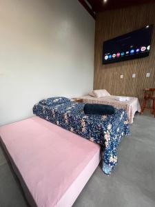 two beds in a room with a tv on the wall at Habitación Maninha in Pântano Grande