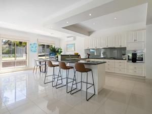 une cuisine avec des armoires blanches et des tabourets de bar dans l'établissement Jacksons Coast House, à Mount Eliza