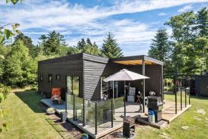 a black tiny house with a patio and an umbrella at OH520-Hadsund-Sletten-132 in Hadsund