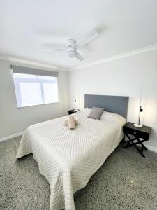 een witte slaapkamer met een bed en een plafondventilator bij Sunset Beach Holiday Park in Geraldton