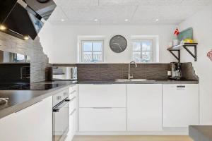 a kitchen with white cabinets and a clock on the wall at OH292-Hadsund-Stenkisten-108 in Hadsund