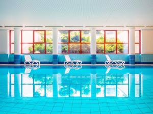 - une piscine avec 2 chaises et des fenêtres dans l'établissement Mercure Jelenia Góra, à Jelenia Góra
