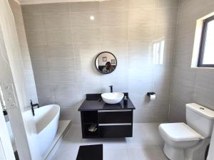 a bathroom with a sink and a toilet and a mirror at 2nd street ibex Apartment in Lusaka